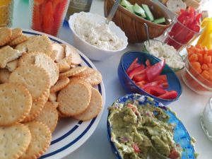 Zu sehen sind Gemüsesticks, Dips und Cracker in Schüsseln.